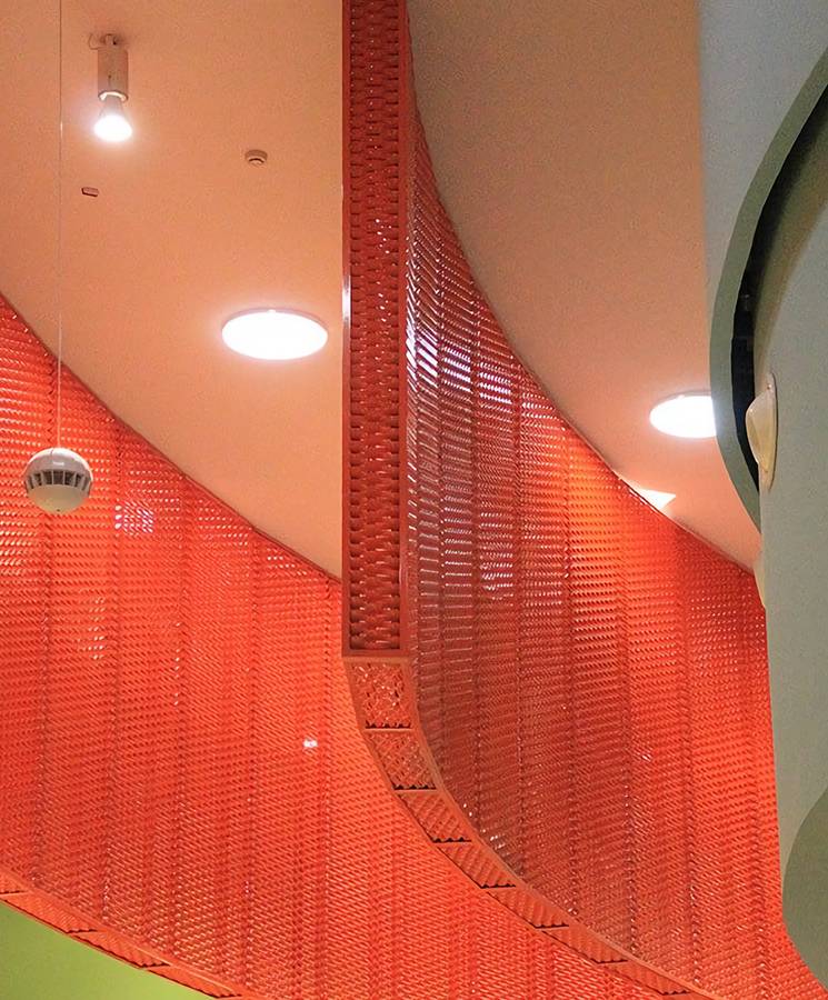 The orange false ceiling is made of expanded metal panels.