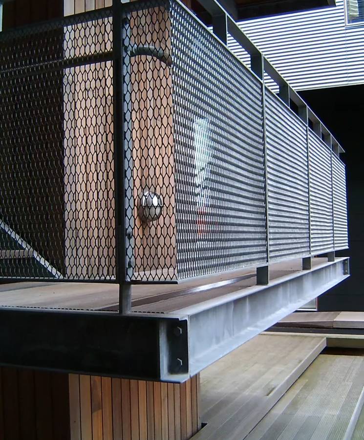 The cantilevering balcony is infilled with black expanded metal sheets.