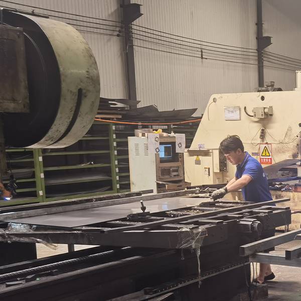 A worker is cutting the edges of perforated sheets.