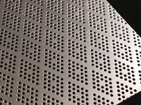 Perforated stainless steel sheet with round holes arranged in a diamond.