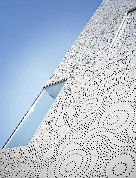The building facade is designed with white perforated metal sheets.