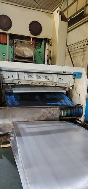 A machine is punching the small round hole metal sheet from coils plates.