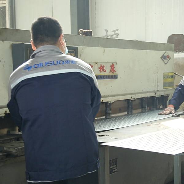 Two workers are shearing pre-gal. perforated sheets.