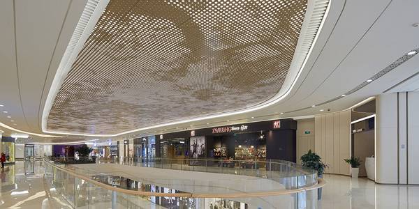 The ceiling of the shopping mall lobby is decorated with perforated metal panels.