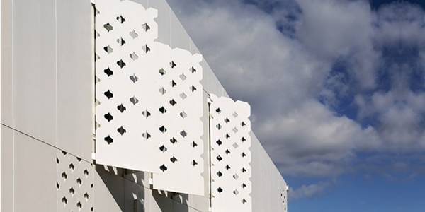 White perforated facade shutters with decorative holes.