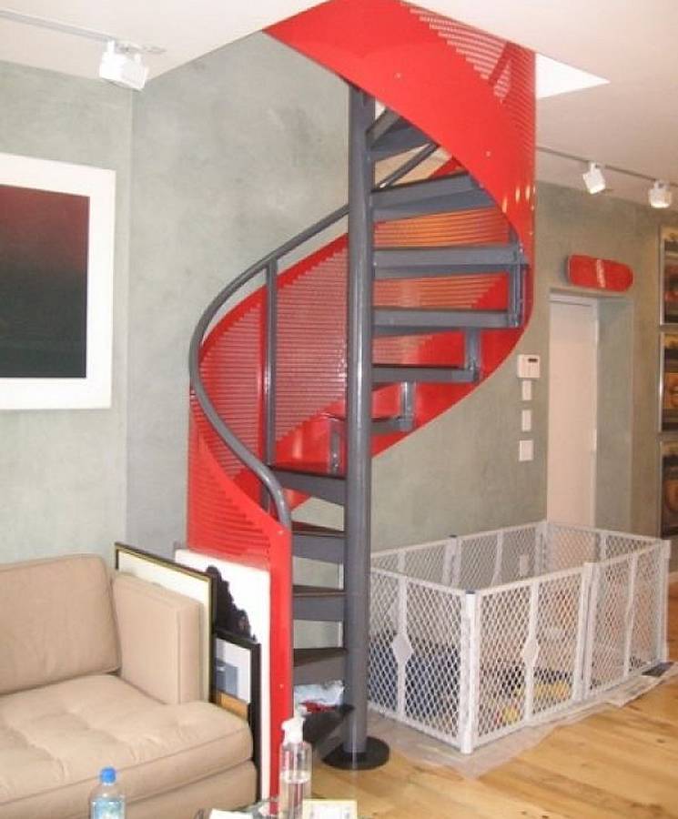 Spiral stair railing designed with red perforated metal panels.