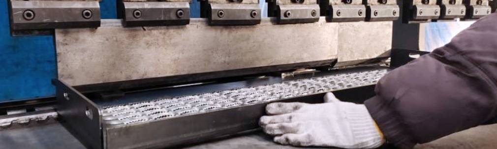 A worker is observing the condition of perforated metal sheet produced by the punching machine.